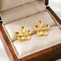 Detailed view of elegant gold-plated flower stud earrings in a wooden jewelry box. - Flower Stud Earrings
