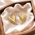 Detailed close-up of golden heart-shaped stud earrings in a rustic wooden gift box - Long Tailed Heart