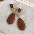 Handcrafted vintage wooden earrings with woven straw spheres on a beige linen background - Geometric Straw Woven Teardrop (28420D)