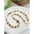 Gros plan d'un collier vintage en perles d'œil de tigre avec fermoir doré - Mélange Perle Oeil de Tigre / 43cm / Brun Blanc Or