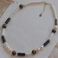 Gros plan d'un collier de perles vintage avec œil de tigre et chaîne plaquée or - Perle Coquillage Oeil de Tigre / 38+5cm / Mélange Brun Noir Blanc
