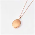 Vue détaillée d'un collier médaillon ovale en acier inoxydable or rose, fini lisse. - Or rose