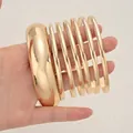 Elegant gold-tone metal bracelet set featuring one wide dome bangle and multiple thin rings. - 6778801HB