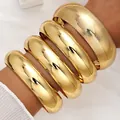 Chunky gold bangle bracelet set featuring three smooth and one textured wide metal bands - 6778901HB