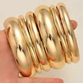 Bold chunky metallic gold bangle set featuring varying widths and a high-polish mirror finish. - 6780801HB