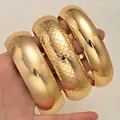 Set of three chunky gold bangles featuring smooth, fish scale, and brushed textured finishes - 6784901HB