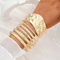 Elegant set of 7 textured gold bangles and wide cuff bracelets for a stylish metal look. - 6785001HB