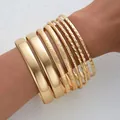 Elegant set of 9 stackable gold bangles featuring smooth and textured metal finishes - 6818801HB