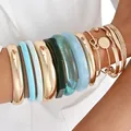 Stackable fashion bangle set with metallic gold and colorful resin bracelets on arm - 6749401HB