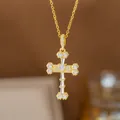 Detaillierte Nahaufnahme eines goldenen Kreuzanhängers mit glitzernden Zirkonia-Steinen - Herz-Baguette-Zirkonia-Kreuz (8415)