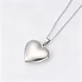 Gros plan d'un médaillon en forme de cœur en argent poli sur fond blanc - Pendentif Médaillon Coeur Lisse / Avec Bélière et Chaîne Croisée Plate / Argent