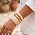 Set of three acrylic and gold-toned metal bangles with marble finish on model wrist - Creamy White Marble Acrylic and Metal 3-Piece Bangle Set (6807601) / Creamy White Combo
