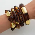 Trendy set of amber acrylic and gold metallic irregular bracelets with a minimalist design. - Amber Textured Bangle 4-Piece Set (6746905HB) / Amber + Gold