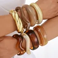 Chunky acrylic and gold-tone irregular bangles set on a model's arm for stylish jewelry. - Irregular Thick Wave Bangle Set (6821801HB) / Multicolor Combo (Gold Brown White)