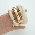 Chunky cream marble acrylic and gold-tone metal bangles set presented in hand - Acrylic Metal Bangle 3-Piece Set (6787401) / Gold and Beige Combo
