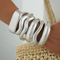 Chunky silver acrylic bangles in irregular wavy designs on a model's arm - Silver Irregular Wave Bangle Set (6801101HB) / Silver