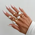 Elegante set di anelli con perle barocche irregolari dorate su una mano con manicure - Modello 7318 / Set da 7 pezzi / Oro