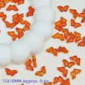 Close-up of translucent orange butterfly glass beads with gold foil effect for DIY - 15x10mm / Orange