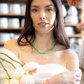 Lifestyle-Foto eines Models mit einer leuchtend grünen Natursteinkette und Rosen - Smaragdgrün/Rosa Armband-Set