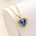 Close-up of heart-shaped blue crystal pendant necklace with gold angel wings detail. - Blue Heart Pendant (D)