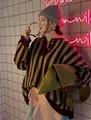 Close-up of striped oversized knit sweater with half-button collar in a chic setting. - Olive Green