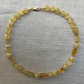 Detailweergave van een ketting met gefacetteerde gele natuursteen kralen op stof - Ketting 9 (38+5cm)