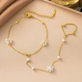 Dettaglio di una catena per mano dorata in acciaio inox con piccoli fiori bianchi. - Stile Perla e Fiore Bianco (E2289)
