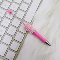 Eleganter rosa DIY Perlen-Kugelschreiber mit Deko-Perlen auf weißer Computer-Tastatur - Perlenstil / Macaron Rosa