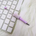 Eleganter lila DIY-Kugelschreiber mit Strasssteinen auf einer weißen Tastatur gelegt. - Perlenstil / Helles Lavendel