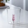 Macro detail showing a clear glass drinking cup with a pink 3D bunny figurine inside - Rabbit