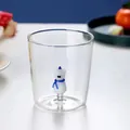 Close-up of clear glass cup with 3D cartoon animal figurine at bottom - Bear with Scarf