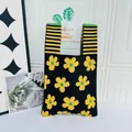 Close-up of black knitted tote bag featuring yellow floral patterns and striped handles - Flower Black