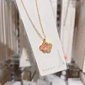 Detail shot of a pink and gold titanium steel four-leaf clover necklace pendant with crystals. - Gold+Pink
