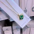 Detail view of a green four-leaf clover pendant necklace in gold-plated stainless steel - Gold & Green