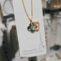 Detailed close-up of a double four-leaf clover pendant necklace in gold-plated steel - Gold & Abalone Shell