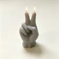 Nahaufnahme einer brennenden grauen Duftkerze in Form eines Victory-Handzeichens für Deko - Grau
