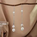 Elegant minimalist silver drop earrings with white pearls hanging from a rustic wooden branch - E2079-6