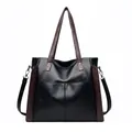 Front view of a large black soft leather tote bag with brown straps and side accents - Black