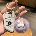 Vista dettagliata della cover per chiave auto bianca con portachiavi a pompon viola - Coniglio Viola