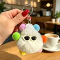 Primo piano di un portachiavi a mostro di peluche bianco con pompon colorati e occhiali - Ciondoli a pallina di fuliggine bianchi