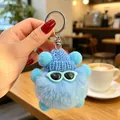 Dettaglio di un simpatico portachiavi a forma di mostro blu peloso con cappellino e occhiali - Ciondoli a pallina di fuliggine blu