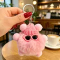 Primo piano di un portachiavi a mostro rosa peloso con cappello lavorato a maglia e occhiali - Ciondoli a pallina di fuliggine rosa