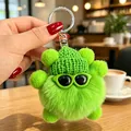 Dettaglio ravvicinato di un simpatico portachiavi in peluche verde con cappellino - Ciondoli a pallina di fuliggine verdi