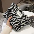 Vista ravvicinata di un'elegante pochette per cosmetici con stampa zebrata bianca e nera - Stile Jacquard Motivo Zebra / Bianco e nero