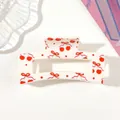 Close-up view of a cream hair claw clip featuring a cute cherry and red bow pattern print - Style G White / 8.5cm Size