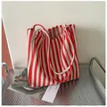 Primer plano de un bolso de lona con rayas rojas y blancas en un entorno artístico - Bolso Tote de Hombro / Rojo