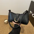 Sophisticated black underarm bag featuring a stylish gold horseshoe buckle detail for women. - Black