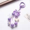 Charming purple beaded keychain featuring iridescent bow and white heart pendant for bags - Purple