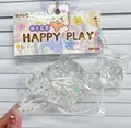 Gros plan d'un jouet squishy en forme de croissant transparent avec perles et étoiles. - Grand croissant transparent plus petite patte de chat