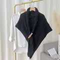 Detailaufnahme eines schwarzen Strick-Dreieckstuchs mit eleganter Schnalle am Kleiderständer - Dreiecksschal mit Lederschnalle (Oberteil) / Schwarz